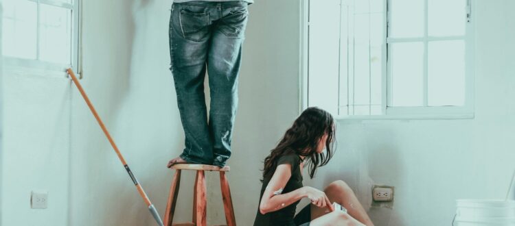 woman in gray tank top and blue denim jeans sitting on bed