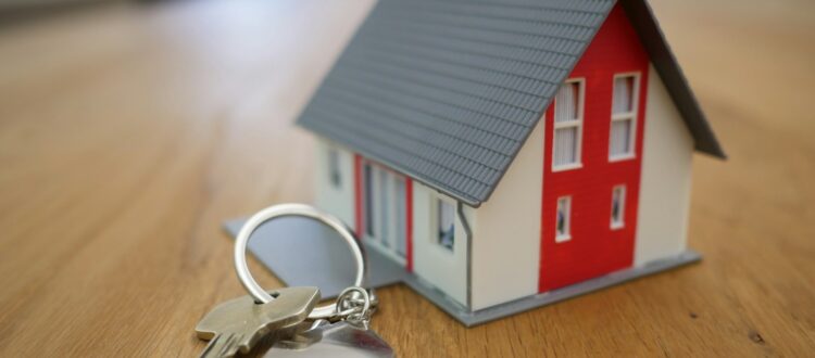 Miniature house with keys on table, displayed above 